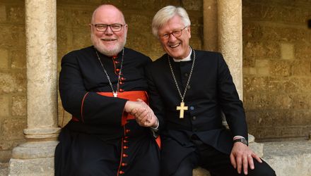 beide sitzen nebeneinander auf einer Mauer vor der Geburtskirche und lächeln